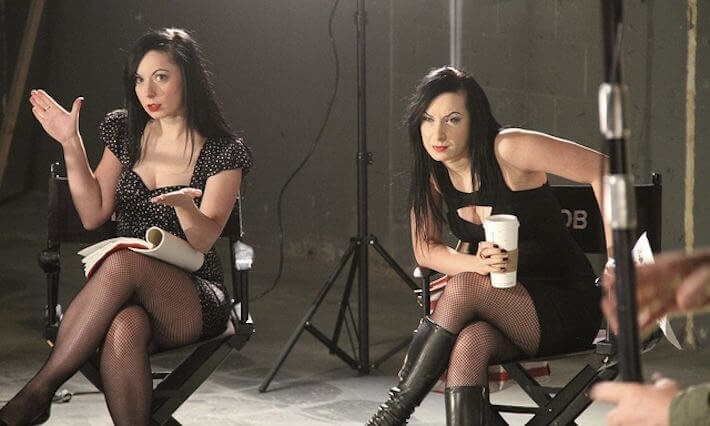 Two twins women are sitting in Directors chairs.