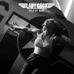 Singer Lady Gaga is laying on a place, pictured in black and white, you may read "Hold My Hand", the title of her new song released for Top Gun: Maverick.