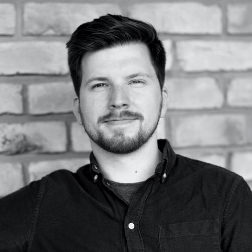 Dan Turner is smiling at the camera with a brick wall behind him.