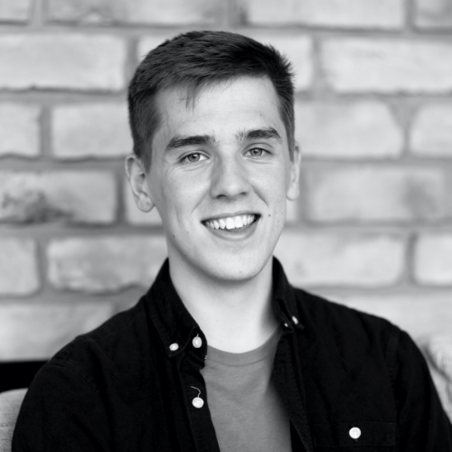Rob Davidson is smiling at the camera with a brick wall behind him.